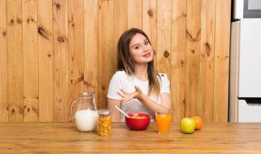 Genç sarışın kadın gelmeye davet için yan ellerini uzatarak kahvaltı olan