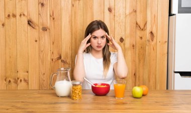 Genç sarışın kadın kahvaltı mutsuz ve bir şey ile sinirli yaşıyor. Negatif yüz ifadesi