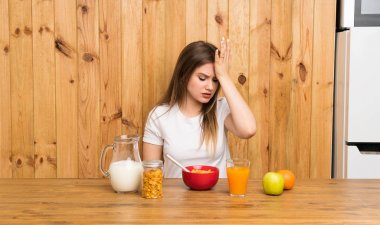 Genç sarışın kadın karışık yüz ifadesi ile şüpheleri olan kahvaltı yapıyor