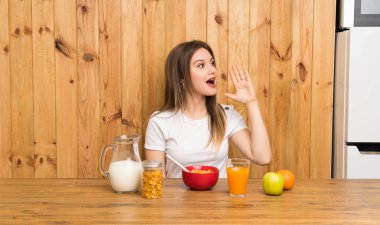 Genç sarışın kadın ağzı tamamen açık bağırarak kahvaltı yapıyor