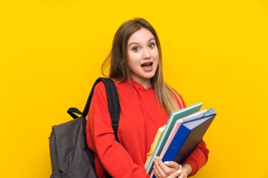 Sürpriz yüz ifadesi ile sarı arka plan üzerinde genç öğrenci kız