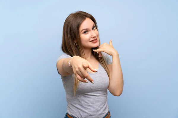 Adolescente Chica Sobre Aislado Azul Pared Haciendo Gesto Teléfono Apuntando —  Fotos de Stock