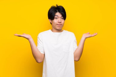 Asyalı adam el kaldırırken şüpheleri olan izole sarı duvar üzerinde