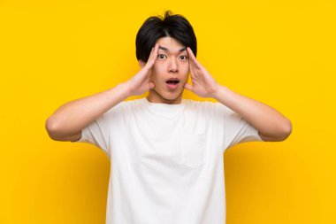 Sürpriz ifade ile izole sarı duvar üzerinde Asyalı adam