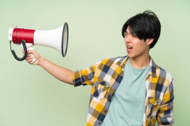 Bir megafon tutan izole yeşil duvar üzerinde Asyalı adam