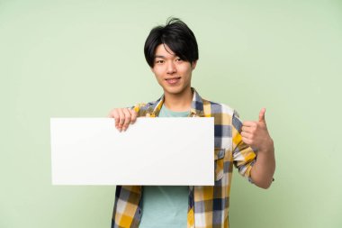 Bir kavram eklemek için boş bir beyaz pankart tutan izole yeşil duvar üzerinde Asyalı adam