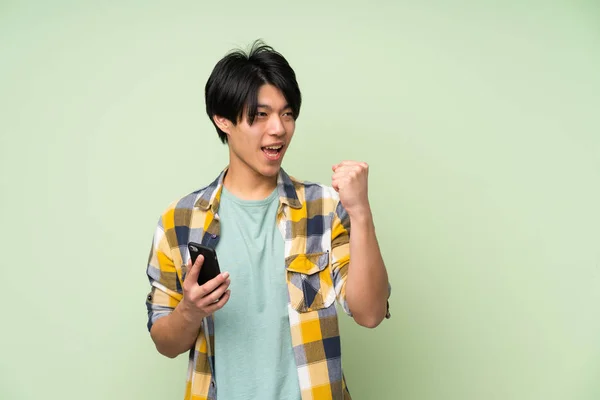 Asiático Hombre Sobre Aislado Verde Pared Usando Móvil Teléfono —  Fotos de Stock