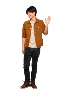Izole beyaz arka plan üzerinde mutlu ifade ile el ile selamlama kahverengi ceket ile Asyalı bir adam tam uzunlukta bir çekim