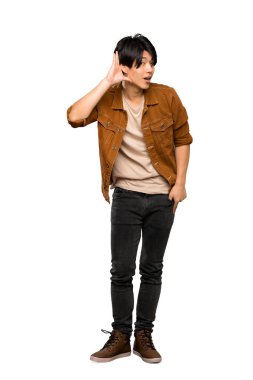 Izole beyaz arka plan üzerinde kulak elini koyarak bir şey dinlerken kahverengi ceketli Asyalı bir adam tam uzunlukta bir çekim
