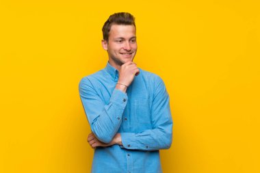 Yüze bakarak izole sarı duvar üzerinde sarışın adam