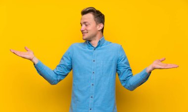 İki eliyle copyspace tutan izole sarı duvar üzerinde Blonde adam