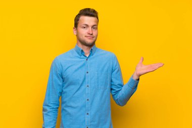 Sarışın adam üzerinde izole sarı duvar yapma şüpheler jest