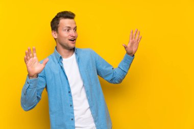 Sürpriz yüz ifade ile izole duvar üzerinde sarışın yakışıklı adam