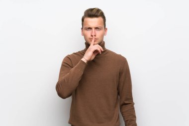 Sarışın adam bir işaret parmağını ağzına koyarak sessizlik jest gösteren izole beyaz duvar üzerinde