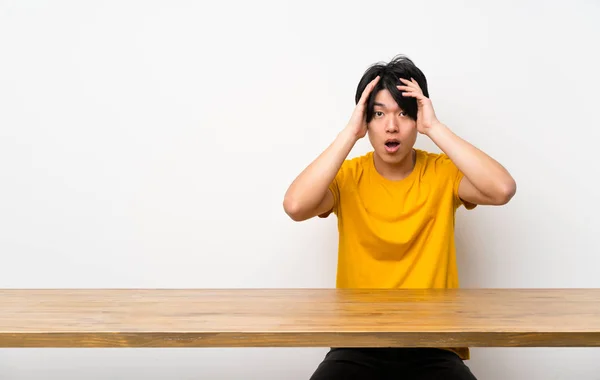 Asian man with yellow shirt with surprise expression