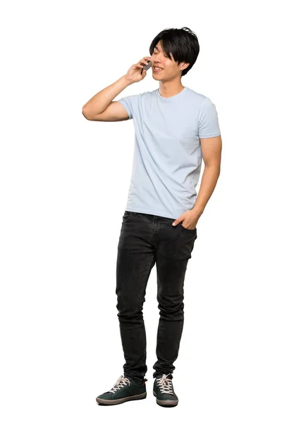 青いシャツを着たアジア人男性が 孤立した白い背景の上に携帯電話との会話を保つフルレングスのショット — ストック写真