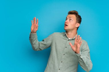 Gergin ve korkmuş izole mavi duvarın üzerinden sarışın adam