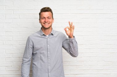Parmakları ile ok işareti gösteren beyaz tuğla duvar üzerinde Blonde adam