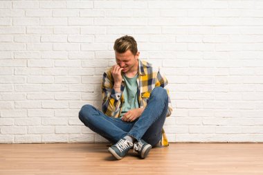 Sarışın adam diş ağrısı ile katta oturan