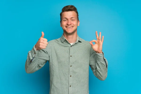 Blond Człowiek Białym Tle Niebieski Pokazując Znak Kciuk Górę Gest — Zdjęcie stockowe