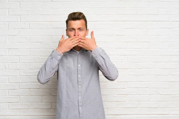 Blond Man Över Vit Tegelvägg Som Täcker Munnen Med Händerna — Stockfoto