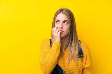 Önlüklü kadın izole edilmiş sarı duvarlı gergin ve korkmuş.