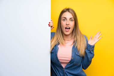 Elinde boş bir levha tutan genç bir kadın. Şaşırmış ve şok olmuş bir yüz ifadesi var.