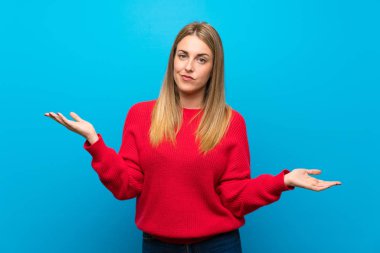 Kırmızı kazaklı, mavi duvarlı bir kadın bir şeyi anlamadığı için mutsuz.