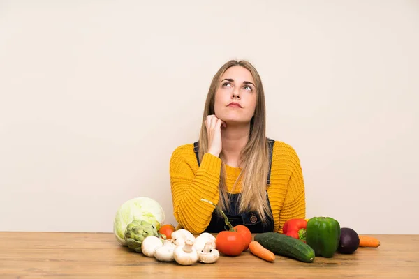 Woman with lots of vegetables standing and thinking an idea