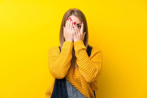 Vrouw Met Overalls Geïsoleerde Gele Muurbekleding Ogen Kijken Door Vingers — Stockfoto