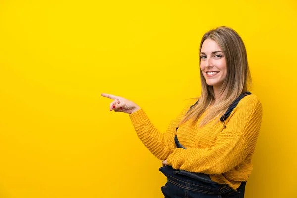 Woman Overalls Isolated Yellow Wall Pointing Finger Side — ストック写真