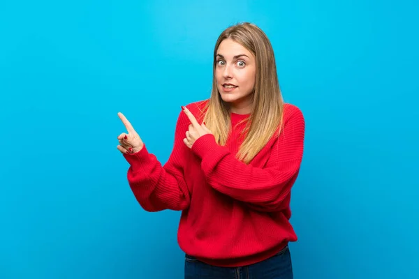 Woman Red Sweater Blue Wall Frightened Pointing Side — Stock Photo, Image