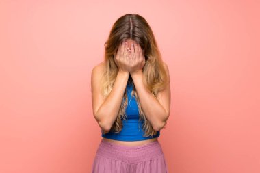 Soyutlanmış, pembe arka planı olan, yorgun ve hasta bakışlı genç sarışın kadın.