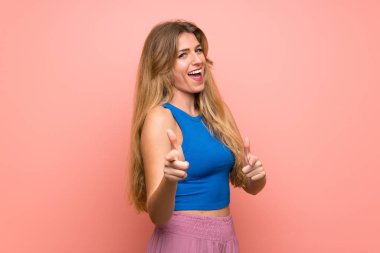 Ön ve gülümseyen izole pembe arka plan üzerinde genç sarışın kadın