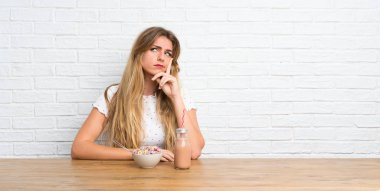 Genç sarışın kadın mısır gevreği kasesi düşünüyor.