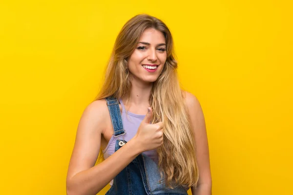 Jovem Mulher Loira Com Macacão Sobre Fundo Amarelo Isolado Dando — Fotografia de Stock