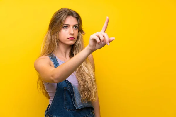 Young Blonde Woman Overalls Isolated Yellow Background Touching Transparent Screen — ストック写真