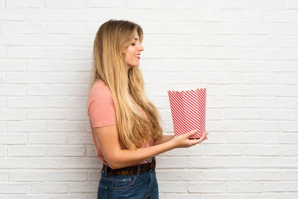 Mujer Rubia Joven Sobre Pared Ladrillo Blanco Sosteniendo Tazón Palomitas —  Fotos de Stock