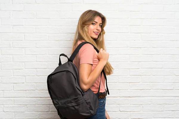 Jovem Loira Sobre Parede Tijolo Branco Com Mochila — Fotografia de Stock