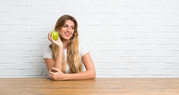 Felice giovane donna bionda con una mela — Foto Stock