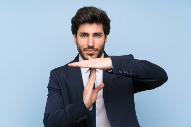 İzole mavi duvar üzerinde işadamı zaman dışarı jest yapma