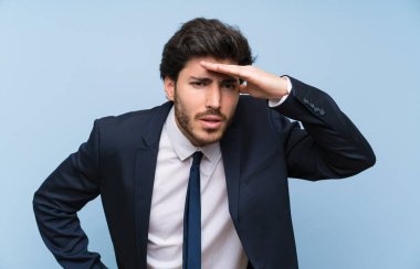 Izole mavi duvar üzerinde Işadamı uzak el ile bir şey bakmak için bakıyor