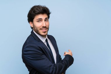 İzole mavi duvar üzerinde işadamı geri işaret