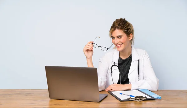 Blonde doctor woman with glasses and happy