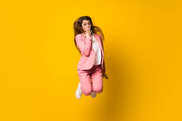 Junge Frau springt über isolierte gelbe Mauer — Stockfoto