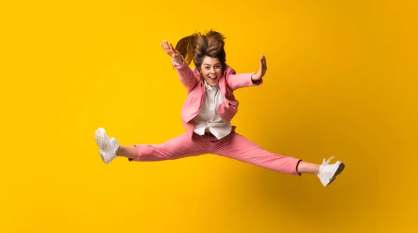 Jovem pulando sobre a parede amarela isolada — Fotografia de Stock
