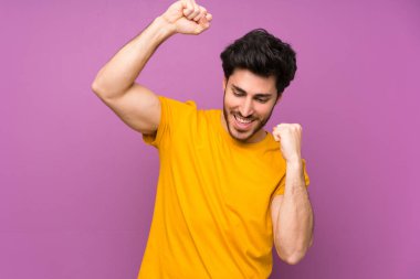 Bir zaferi kutlayan izole mor duvar üzerinde Yakışıklı