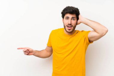 Izole beyaz duvar tarafında parmak işaret ve bir ürün sunan üzerinde Yakışıklı