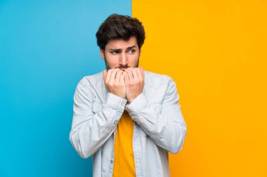 Izole renkli arka plan sinir üzerinde Yakışıklı ve ağıza ellerini koyarak korkmuş