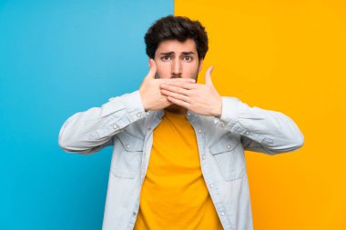 Elleri ile ağız kapsayan izole renkli arka plan üzerinde Yakışıklı